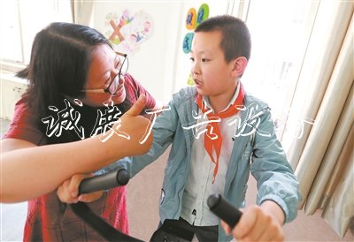 在無錫市廣新小學融合教育資源中心，梁溪區(qū)特教指導中心資源教師陳向華指導小過進行康復訓練，夸贊他有進步。