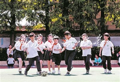 在無錫市廣新小學操場上，隨班就讀學生小瑩、小俊和同學們一起踢足球。陽光下，孩子們臉上綻放出燦爛的笑容。