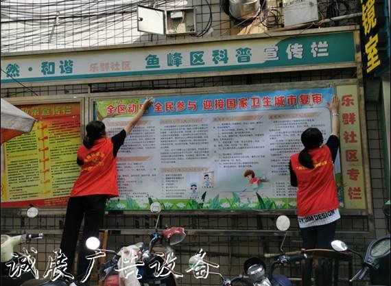 圖為轄區(qū)志愿者正在粘貼創(chuàng)城板報(bào)