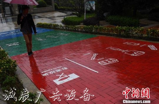 圖為市民走在垃圾分類彩色涂裝步道上，紅色、藍(lán)色、綠色各自代表了垃圾“四分類”元素?！≈芤?攝