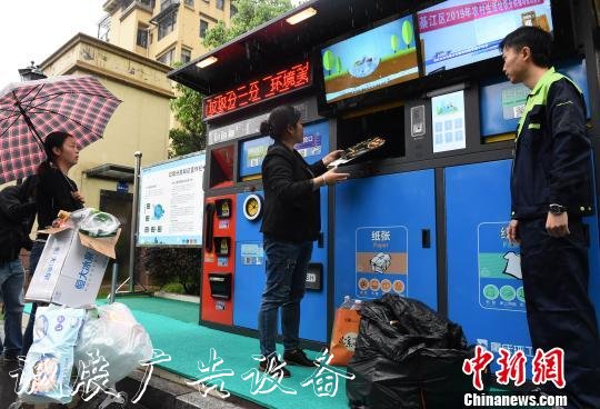 圖為市民在工作人員指導(dǎo)下進(jìn)行垃圾分類投放。　周毅 攝